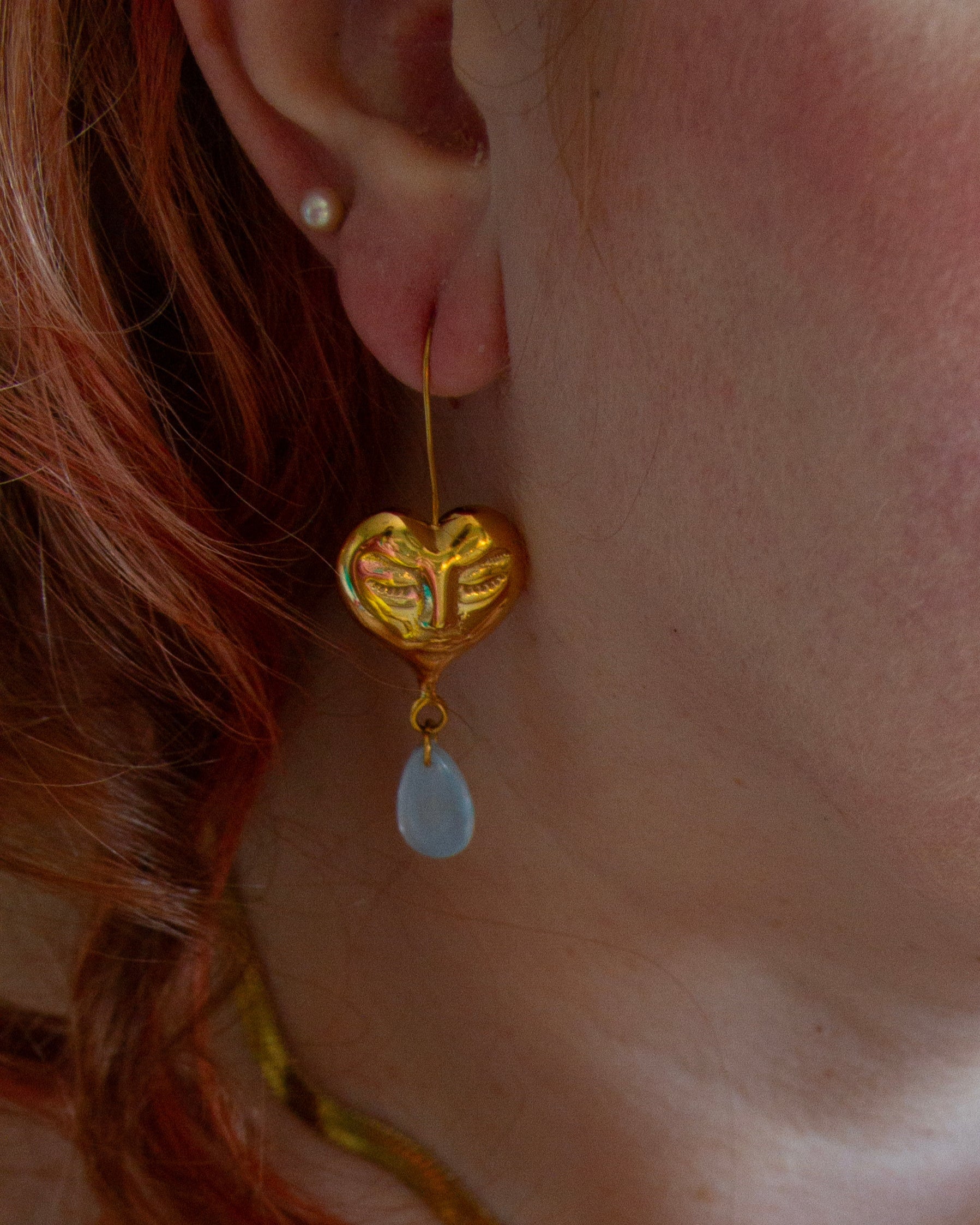 Close-up of a person wearing gold jewelry including earrings, bracelet, and ring.